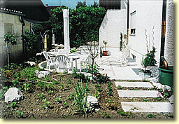 Terrasse mit Natursteinen umrandet von einem naturnahen Gartenbereich